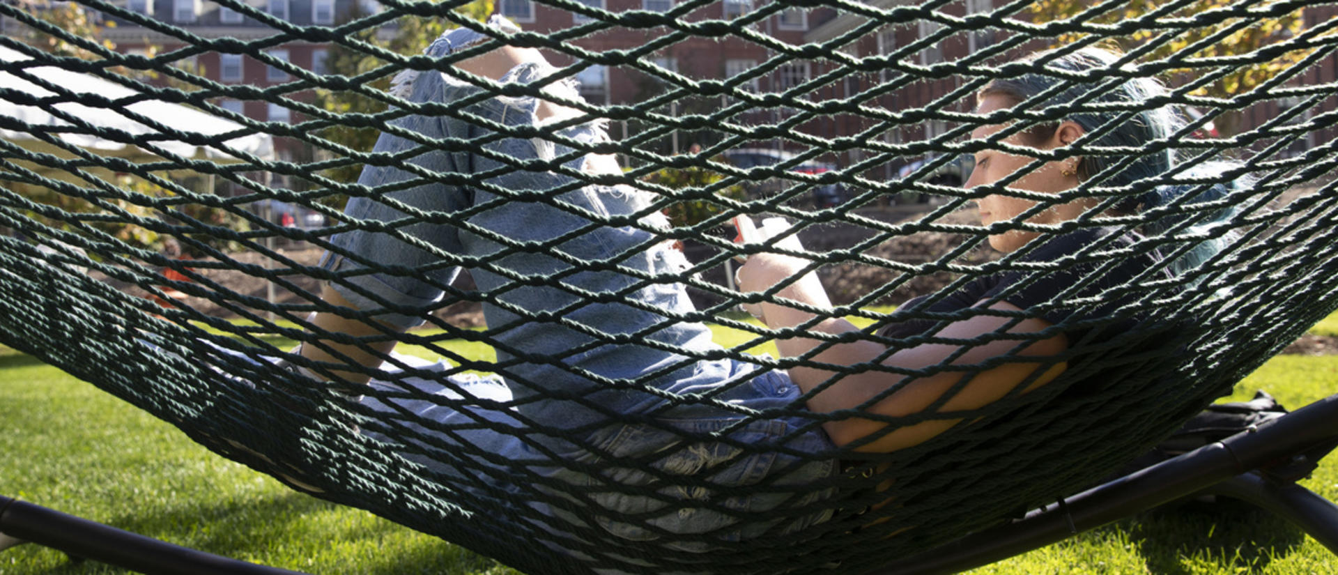 A student lounges in a hammock while reading.